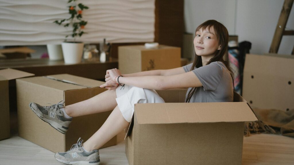 Woman sitting in a packing box.