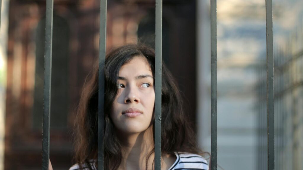 Woman leaning against gate bars