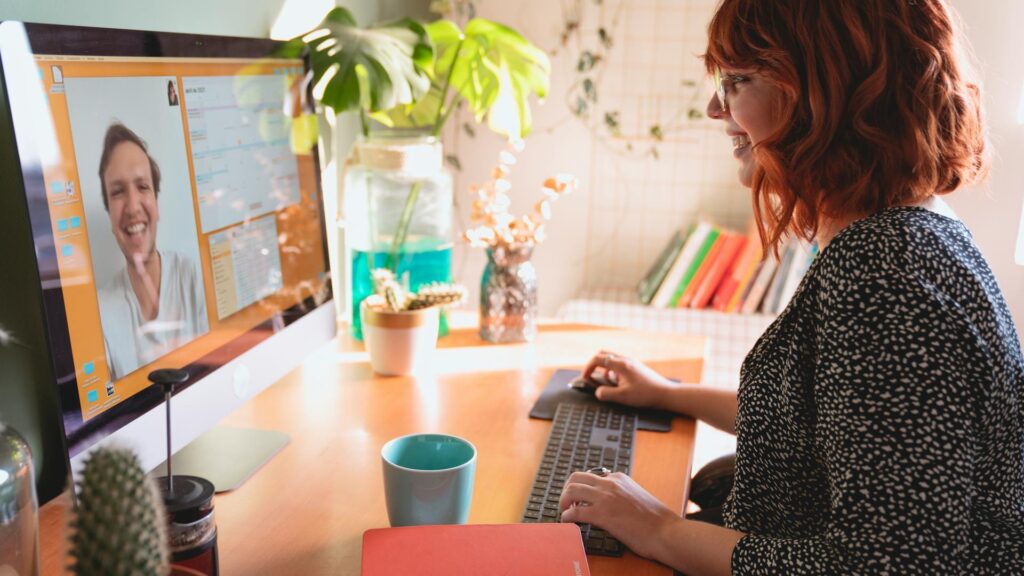 Woman at a desk speaks on a video call.