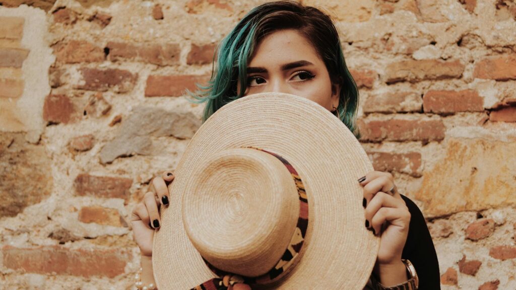 Woman hides her face with a hat.