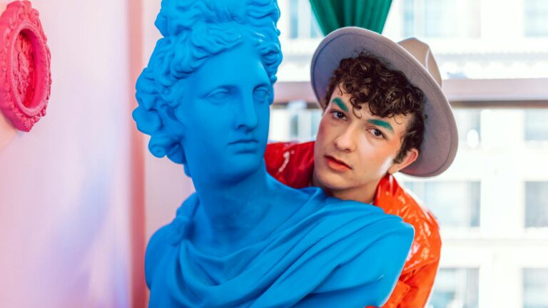 Fashionable man peeks over statue.