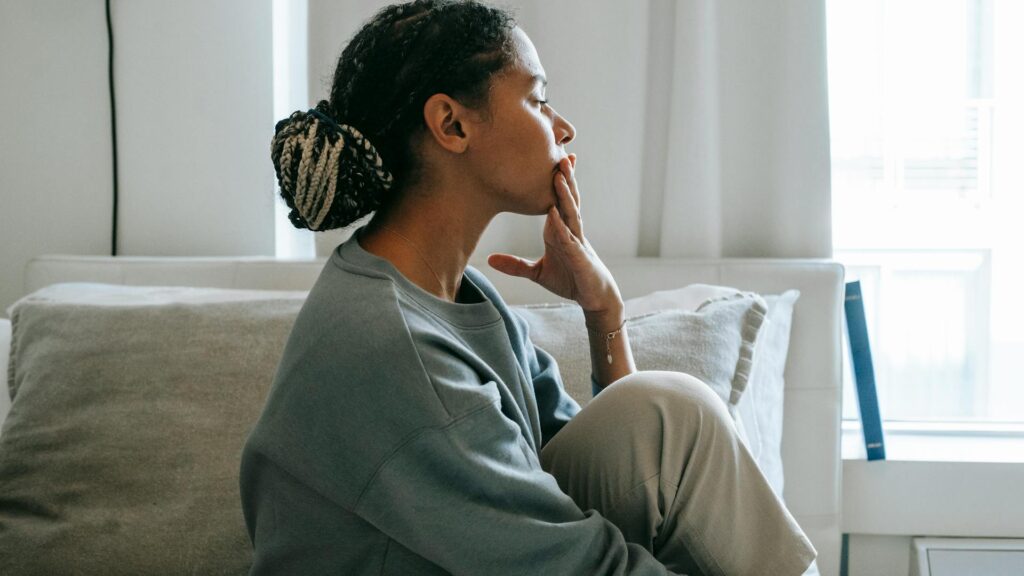 Woman looks out a window sadly.