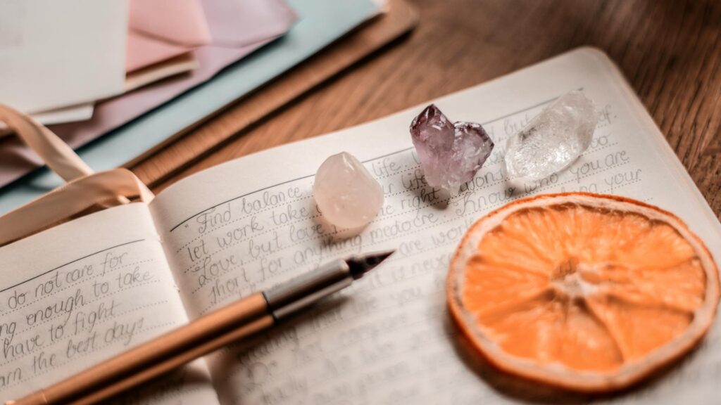 Journal sits with crystals and dried orange slice.