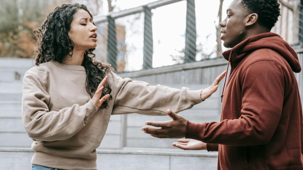 Woman pushes away man in argument.