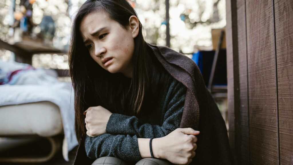 Distressed woman wrapped in a blanket.