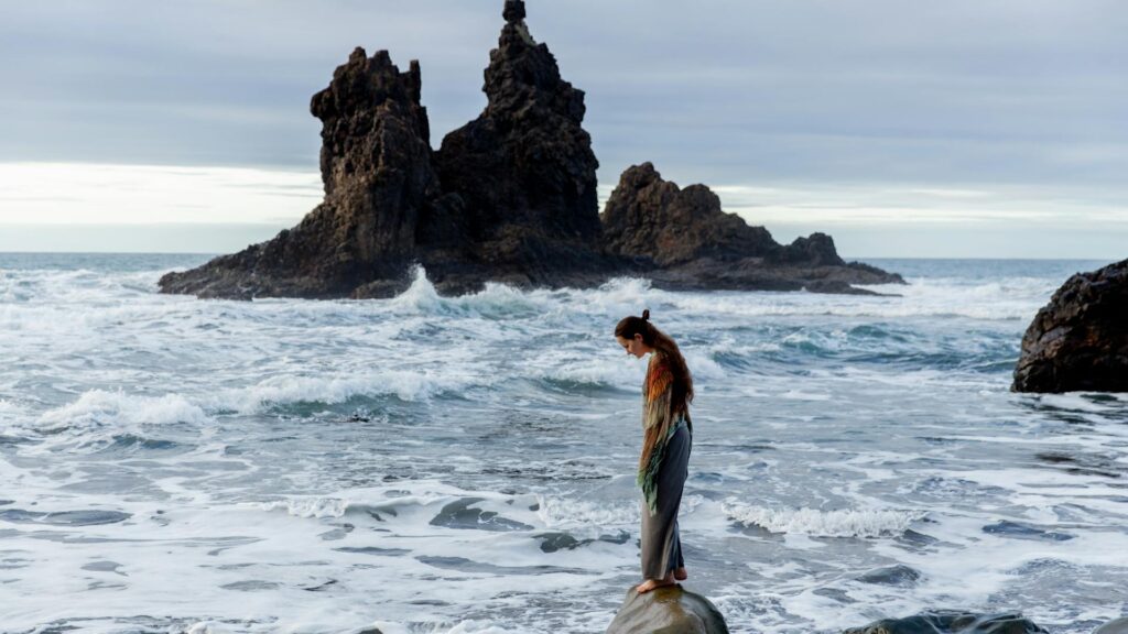 Woman on rock looks into the ocean