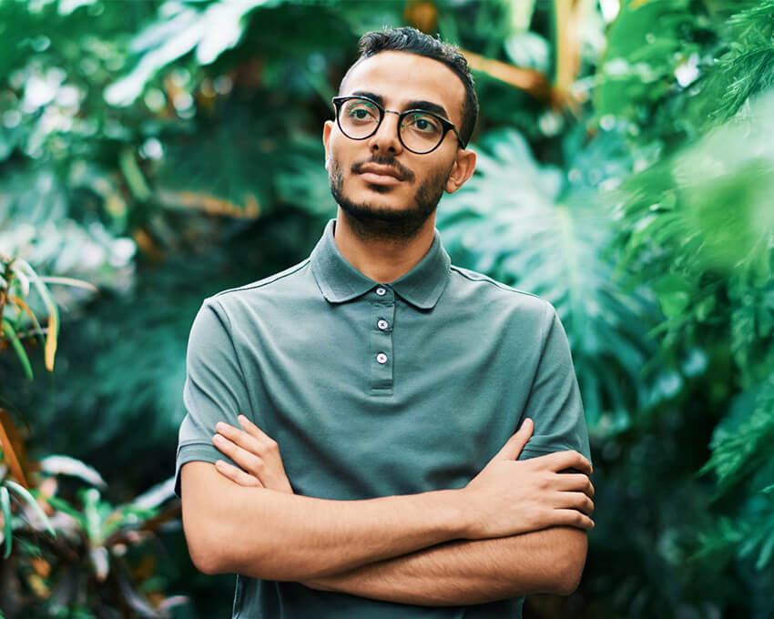 Person standing with arms crossed in a lush green garden