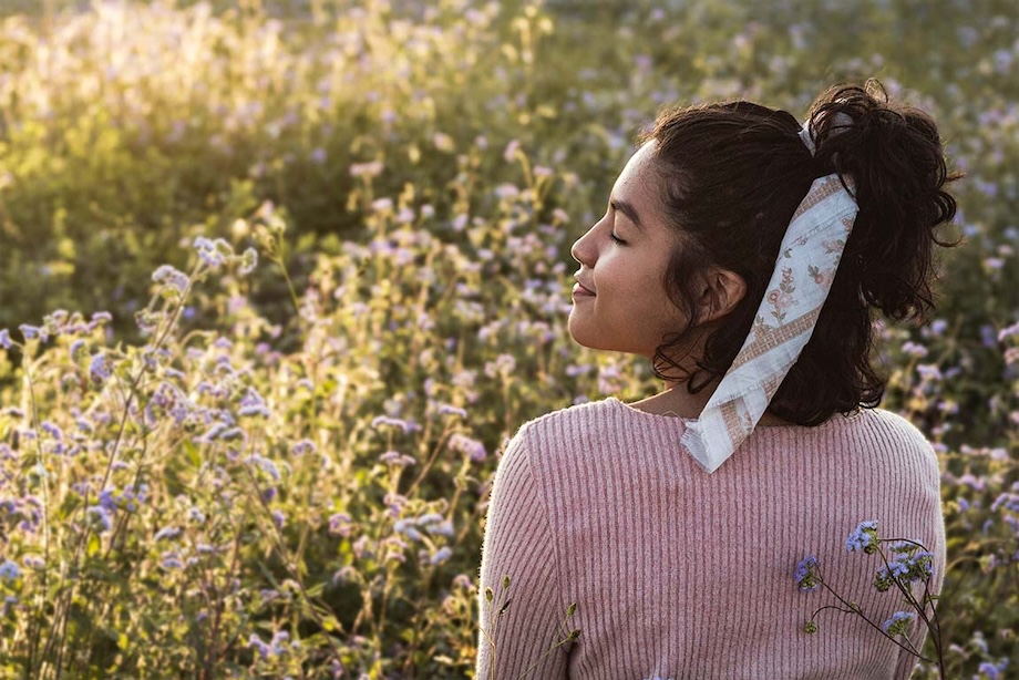 A woman relaxes in a field of flowers.